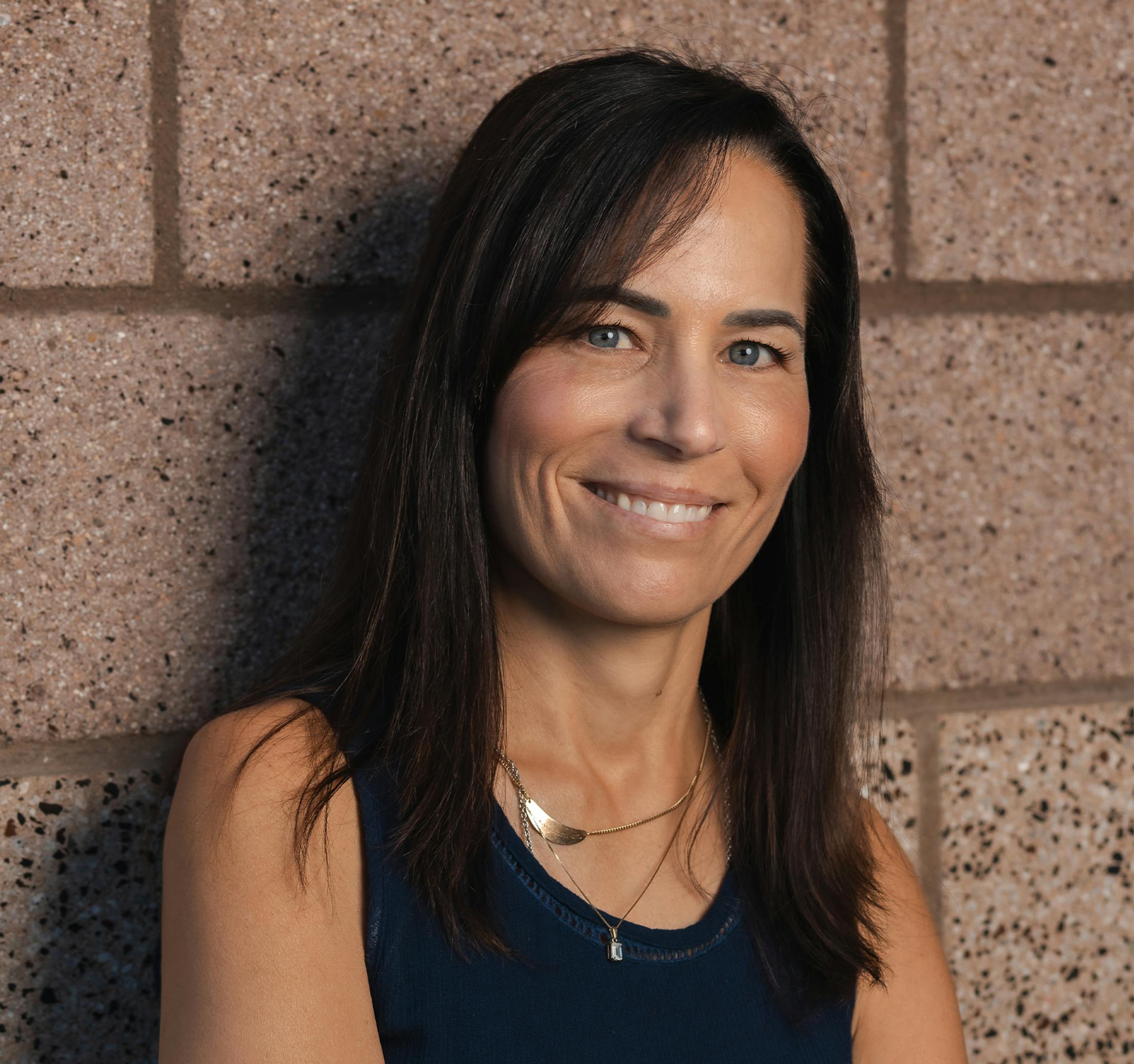 woman smiling with brick wall behind her