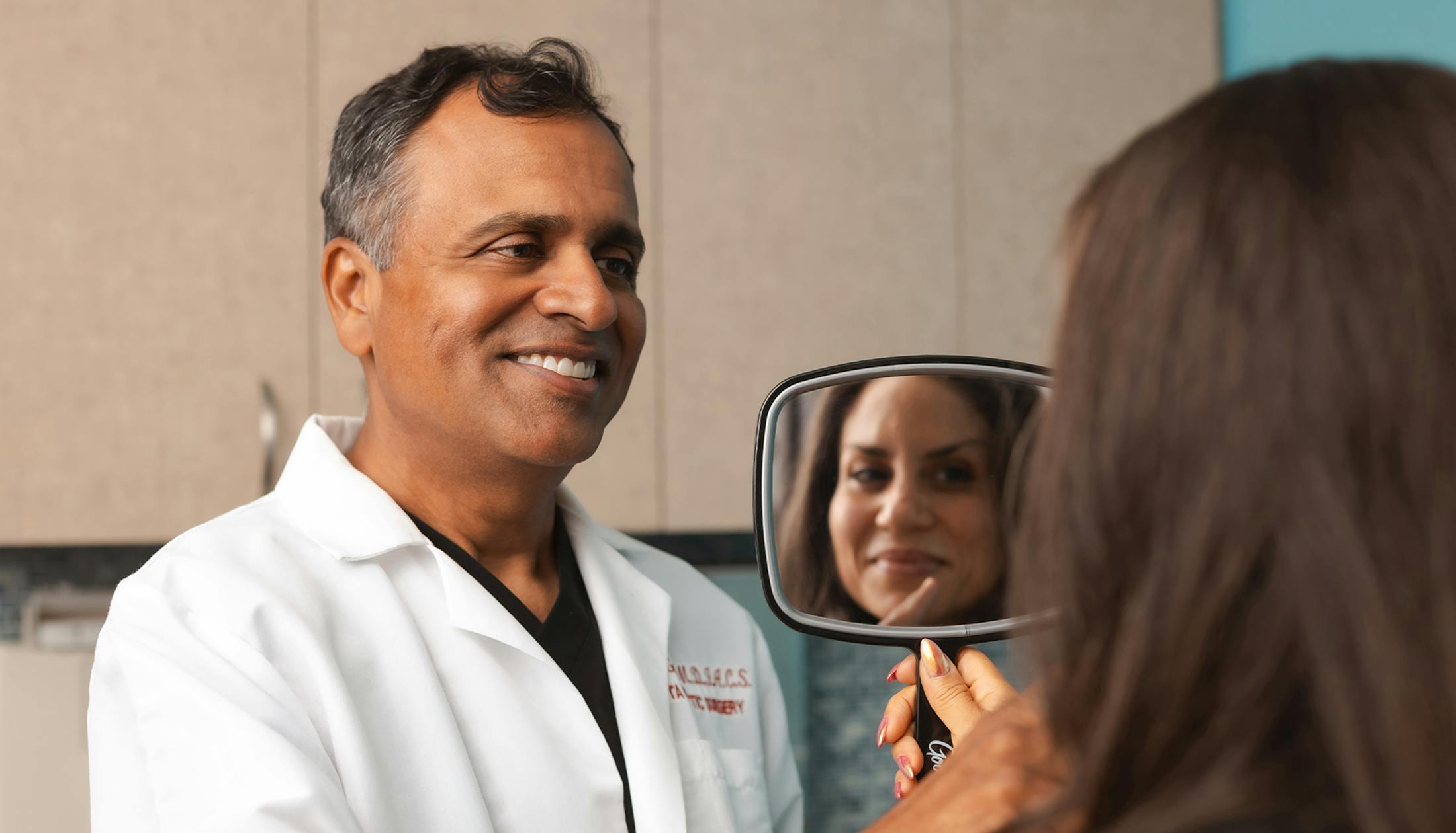 Dr. Abhay Gupta examining patient while she holds handheld mirror