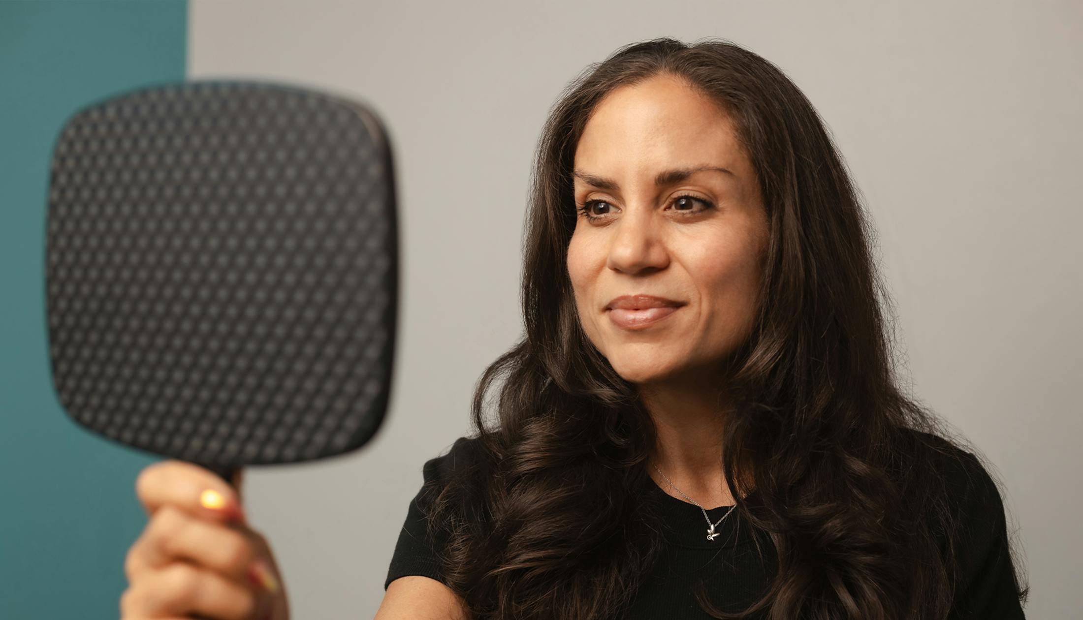 woman looking into handheld mirror