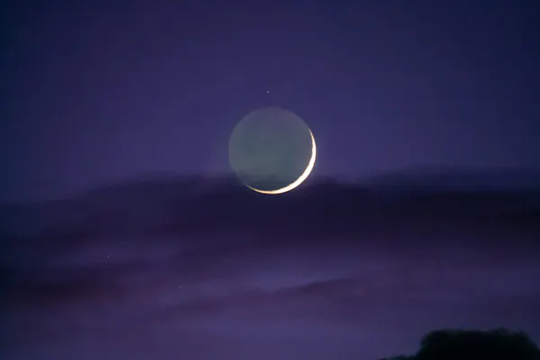 a crescent moon is seen in the night sky