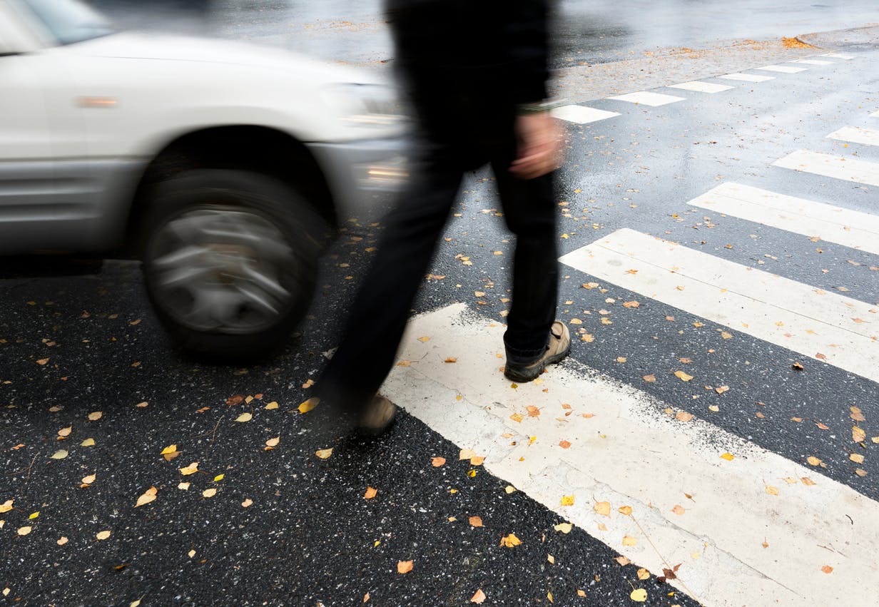 Man on pedestrian crossing, in danger of being hit by car