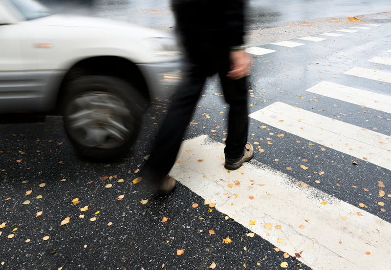 Man on pedestrian crossing, in danger of being hit by car