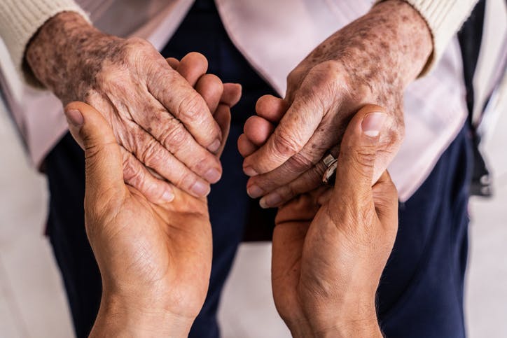 A person holding an elderly woman's hands