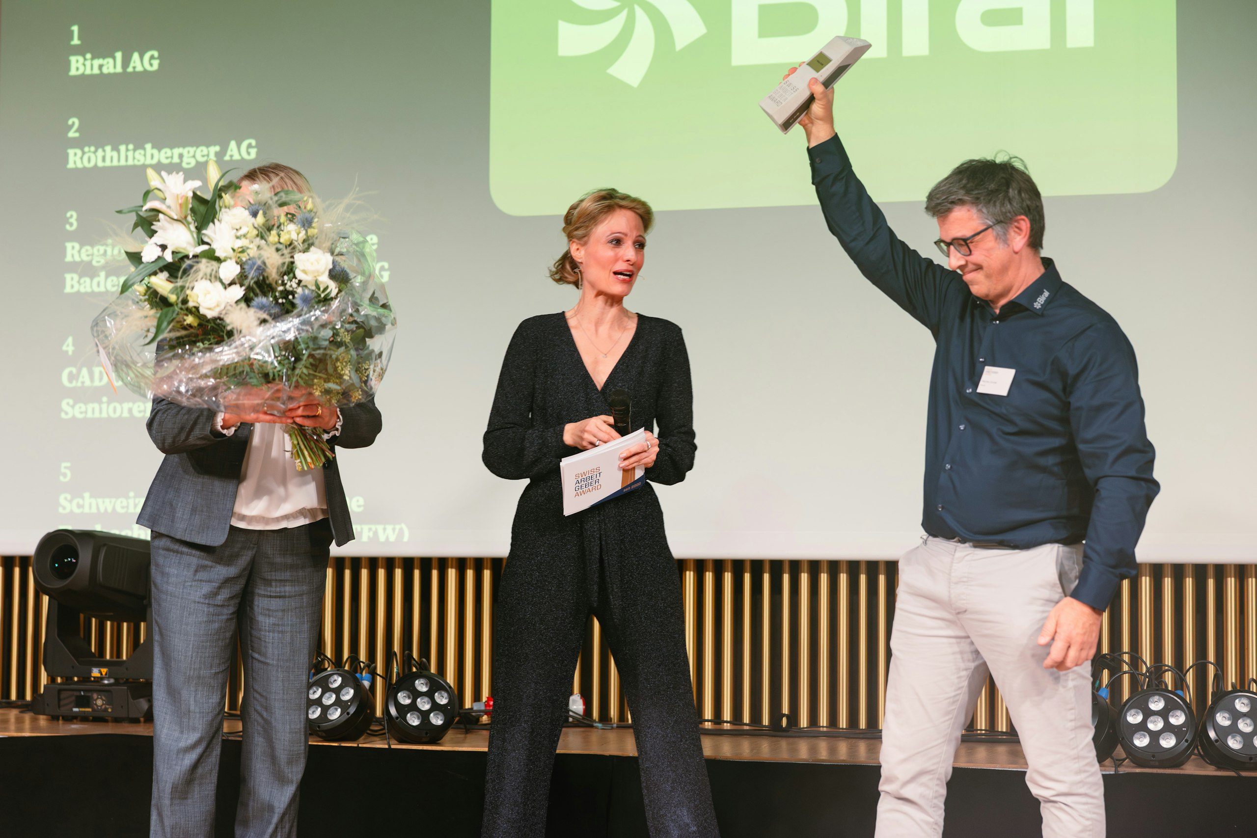Biral Mitarbeitende nehmen den Swiss Arbeitgeber Award auf der Bühne entgegen