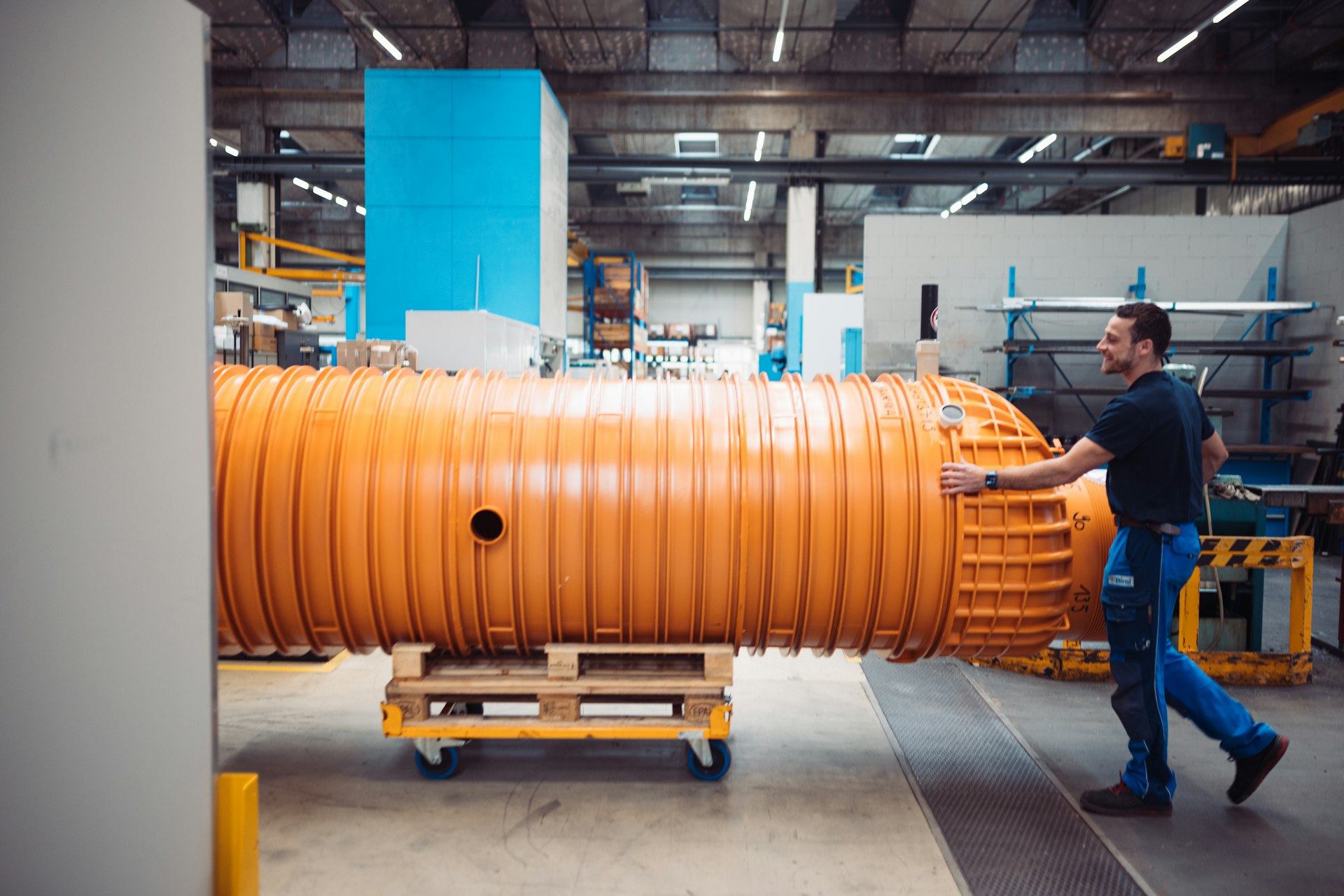 Mitarbeiter transportiert orangen Biral Kunststoff-Pumpschacht in der Produktion