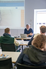 Un formateur explique les principes fondamentaux de la technologie des pompes à un groupe dans la salle de formation.
