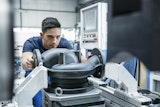Mitarbeiter spannt ein Pumpengehäuse in eine Werkzeugmaschine.