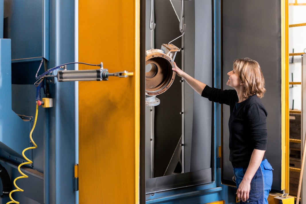 Biral Mitarbeiterin reinigt ein Pumpenbauteil in der Strahlkabine
