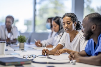 Male and female medical staff sit at a desk looking over documents