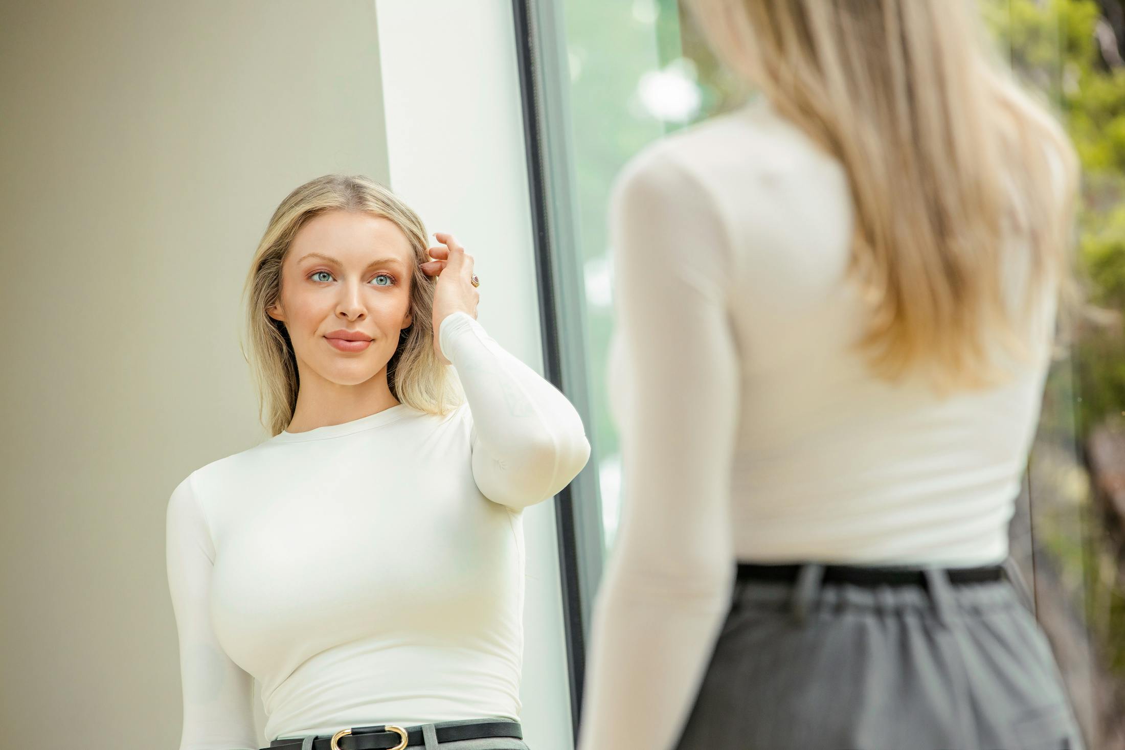 woman looking in mirror touching hair