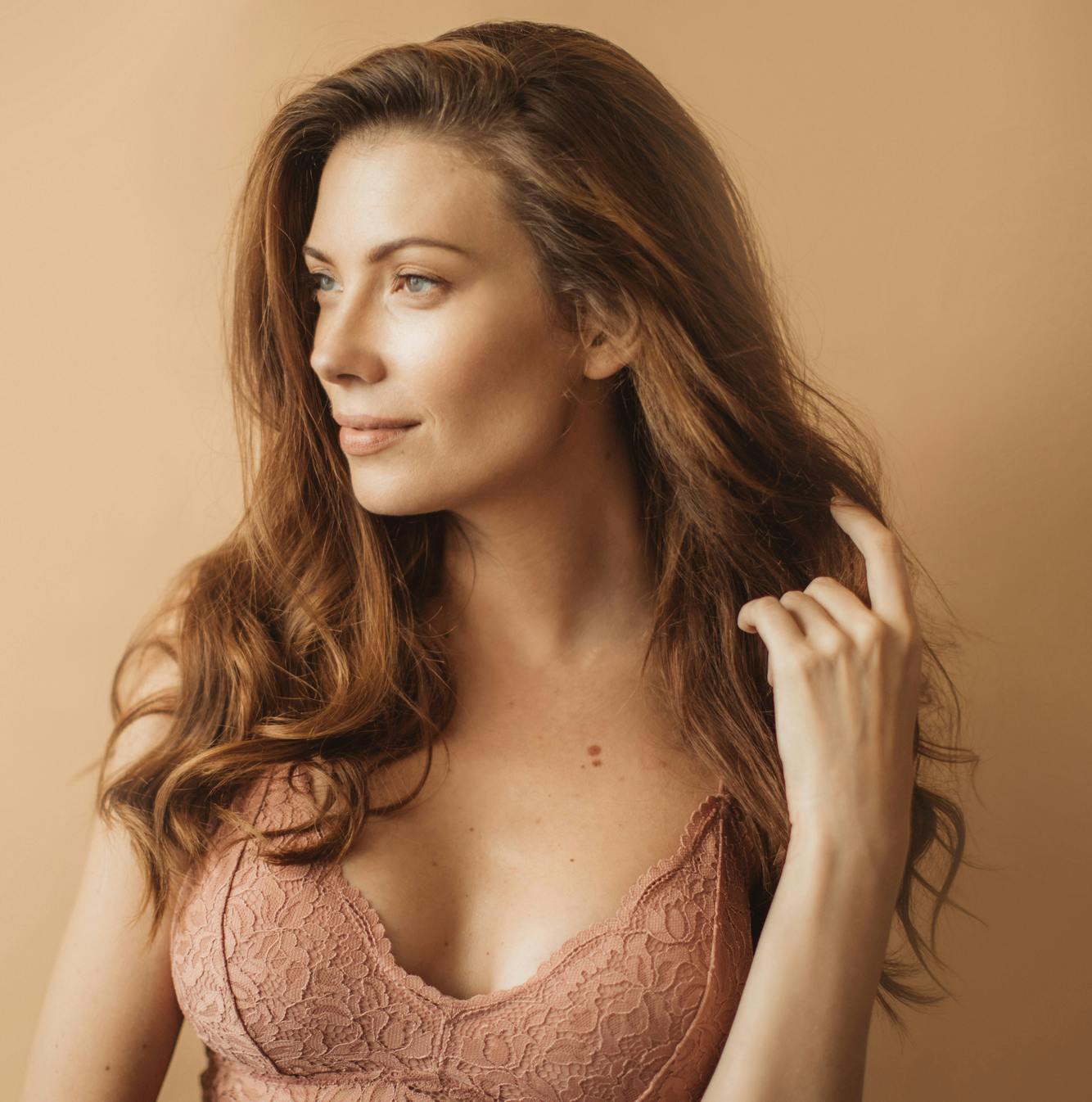 woman in bralette looking to the side touching hair