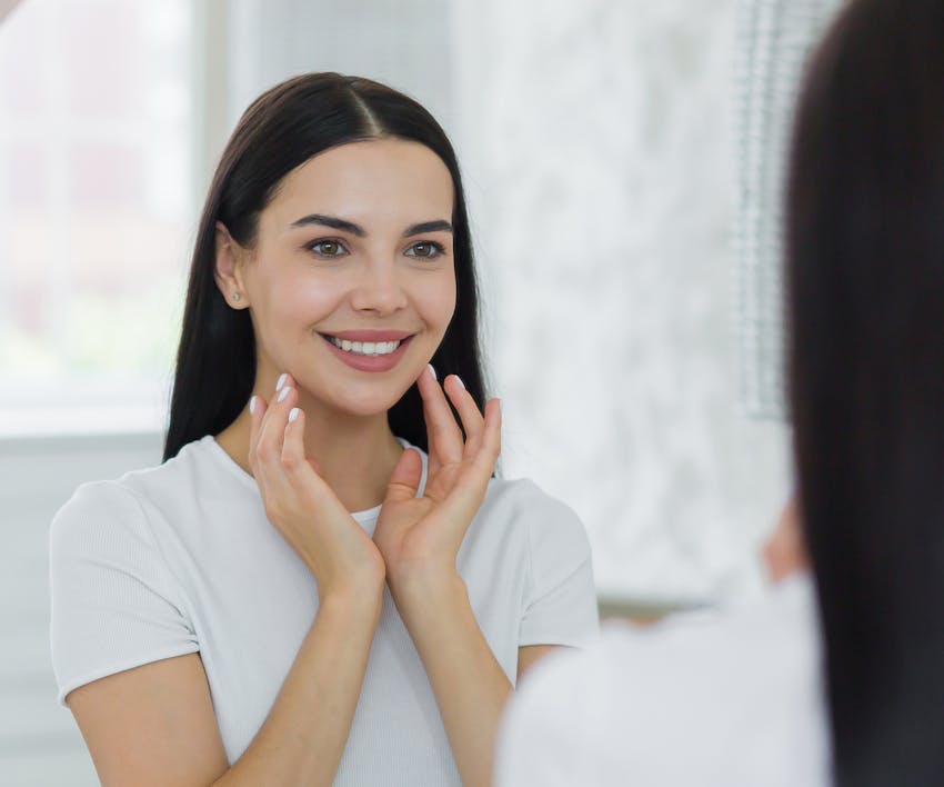Smiling woman looking at her reflection in the mirror