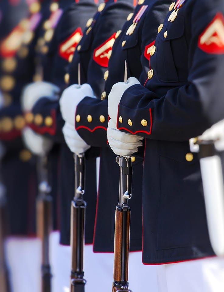 Uniformed honor guard holding rifles.