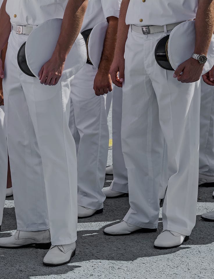 People in white uniforms holding hats