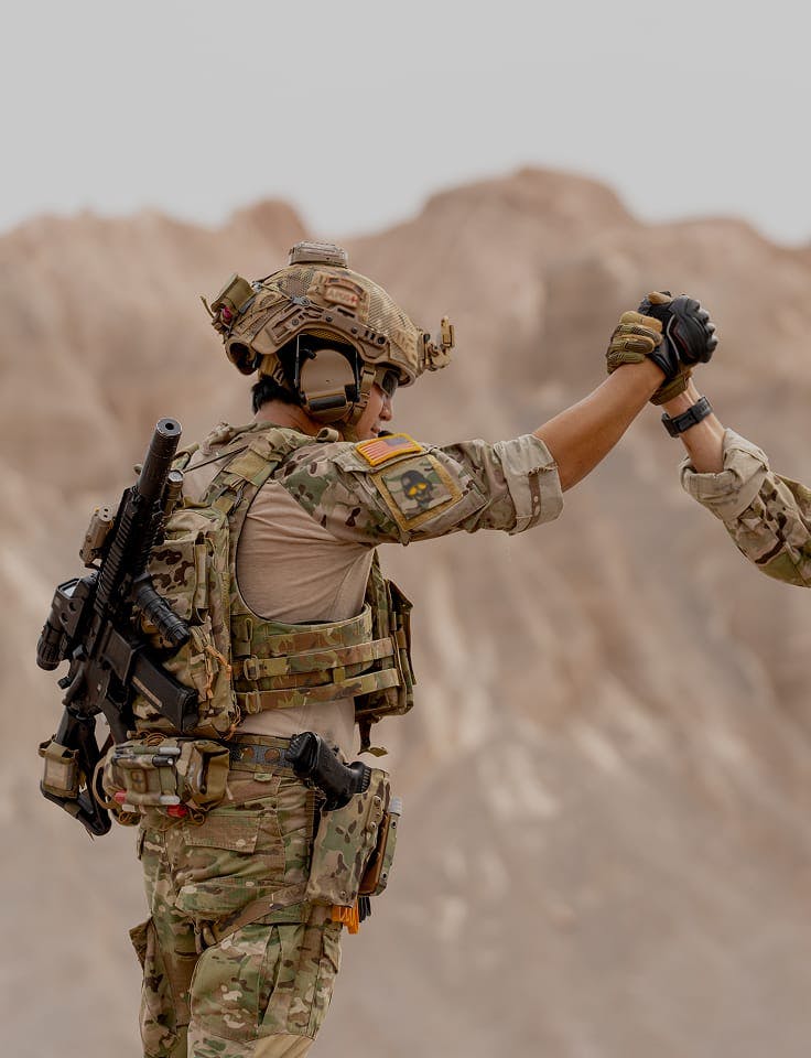 Two soldiers clasp hands in desert