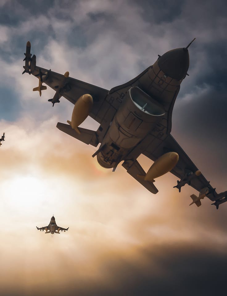 Two fighter jets flying through cloudy sky