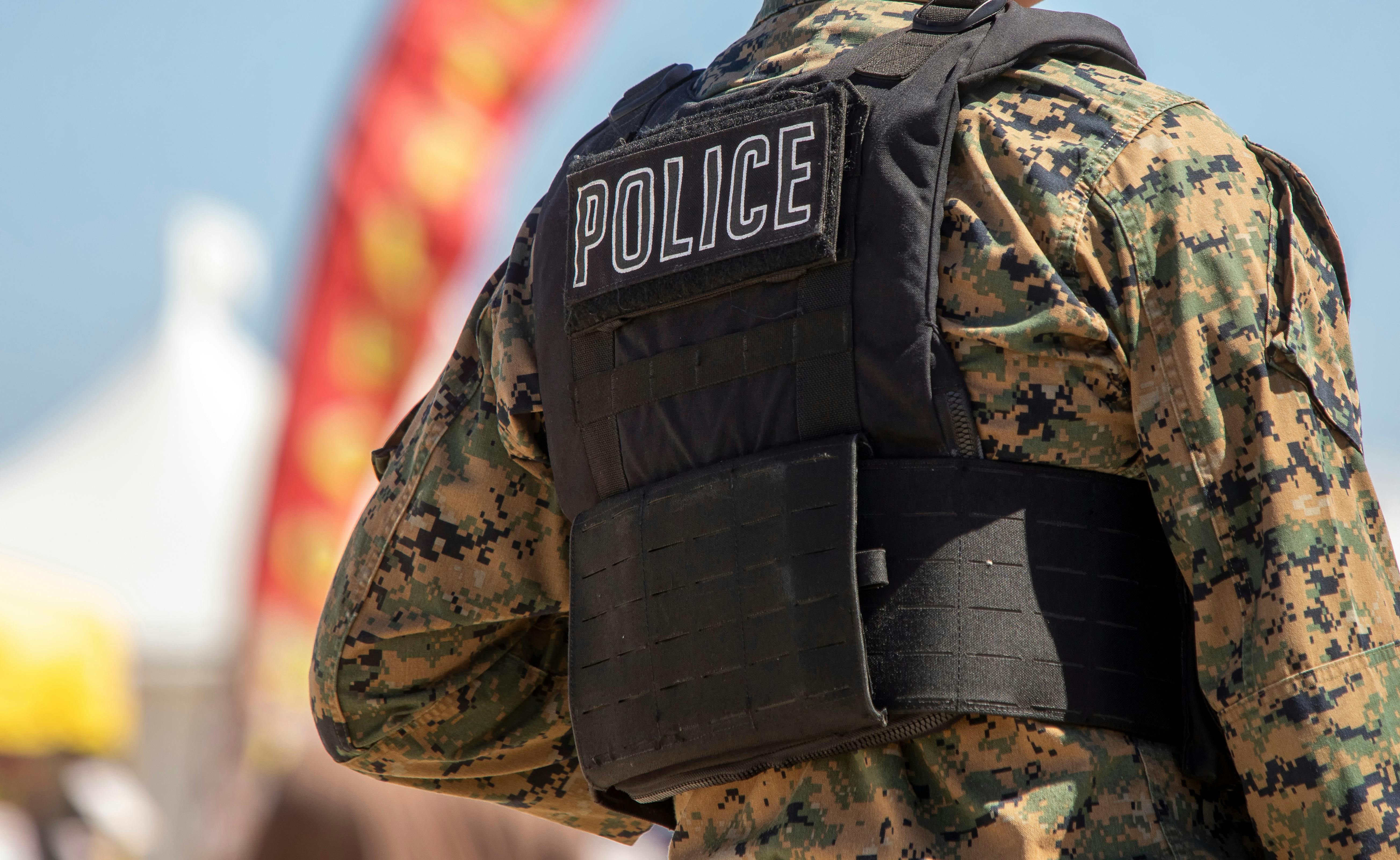 Police written on a body armor vest that is over camouflage military fatigues