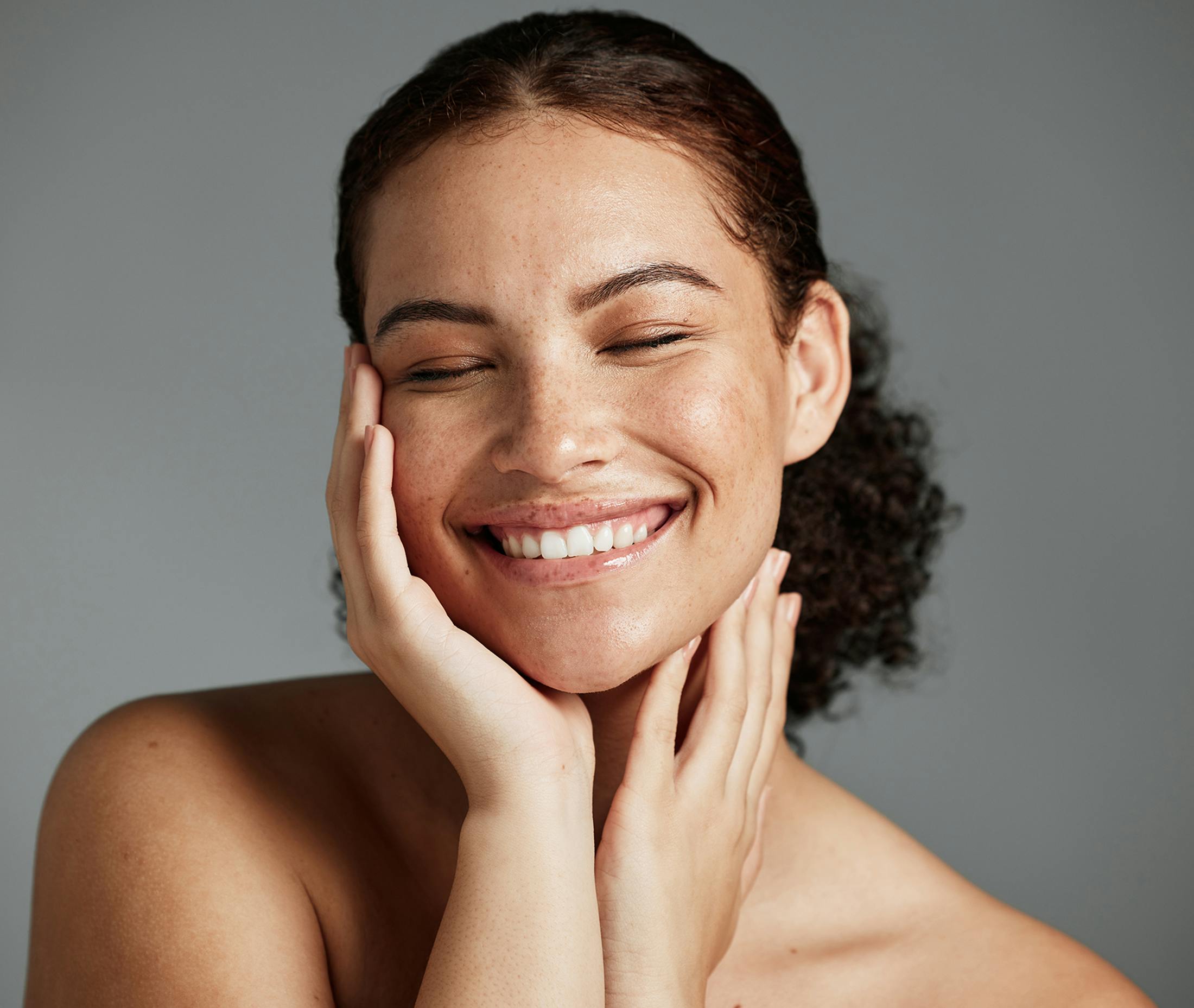 woman smiling holding face