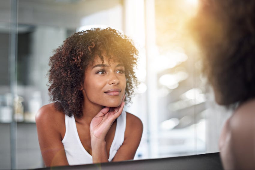 Woman smiling at her reflection in a mirror.