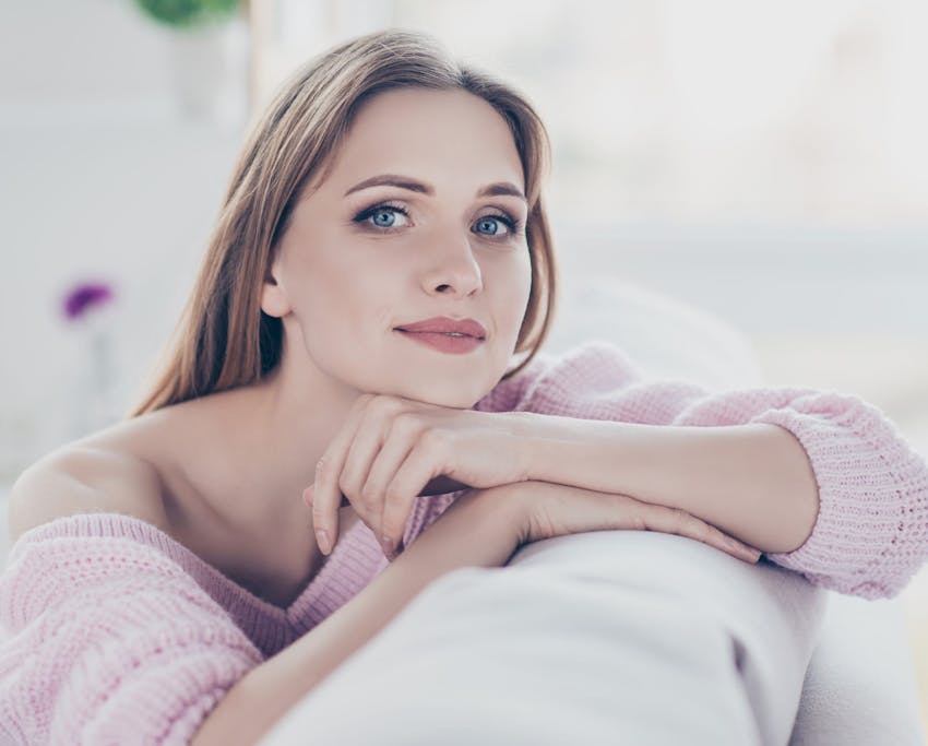 woman leaning her arms and head on the top on the couch