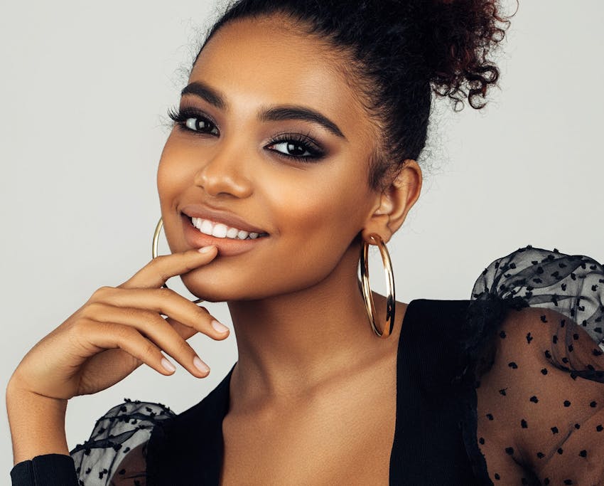 woman with hair tied up and her finger on her bottom lip