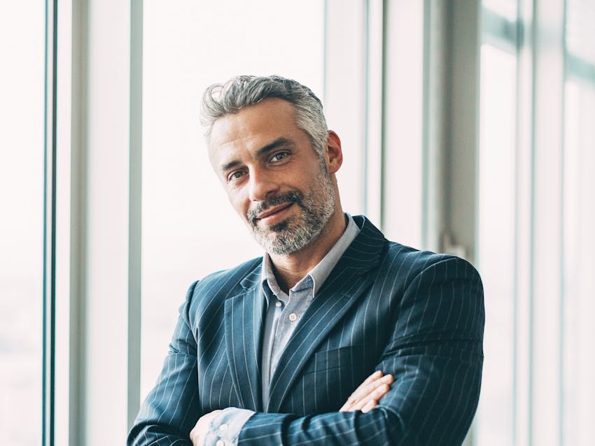 man with his arms crossed standing near window