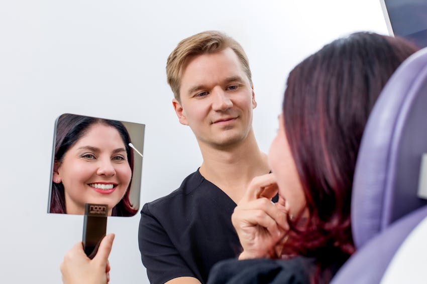 patient looking in handheld mirror while doctor examines her eyes