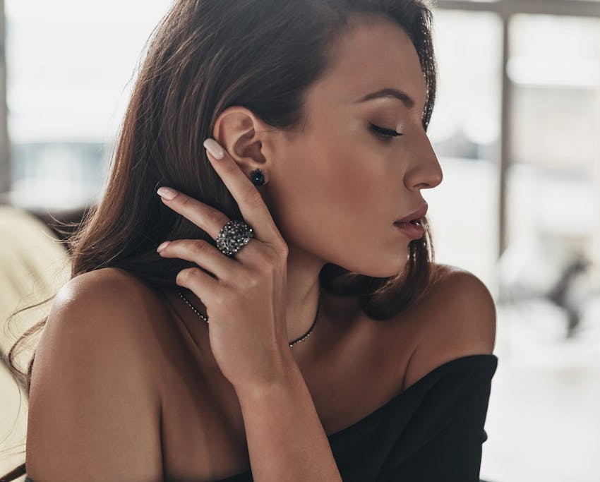 woman looking to the side and moving her hair behind her ear