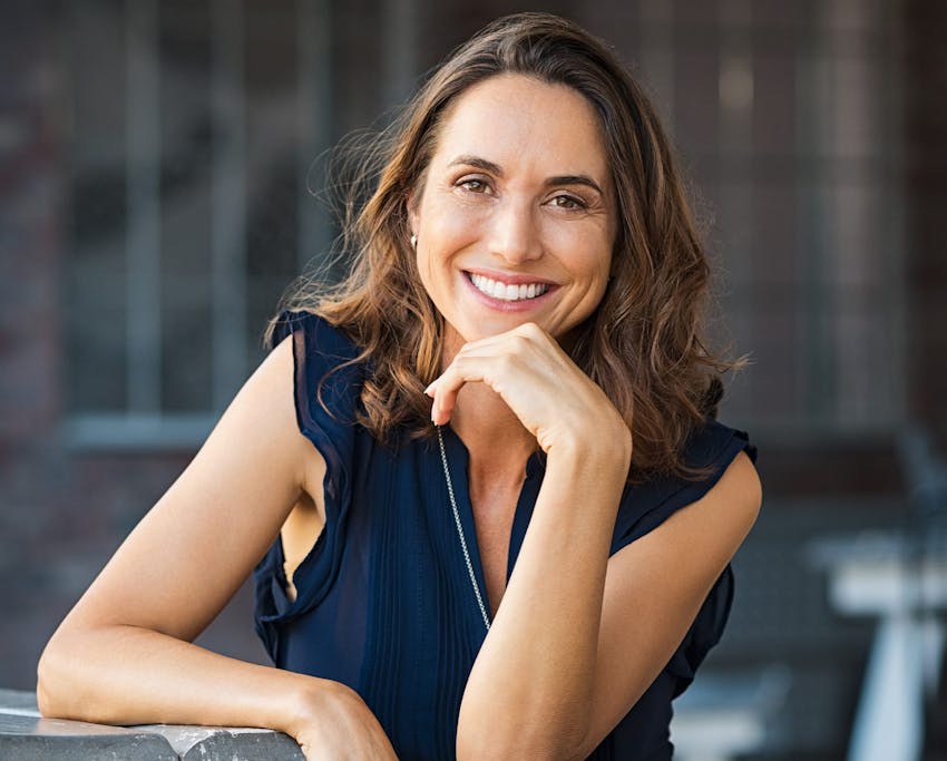 woman smiling with her fingers under her chin