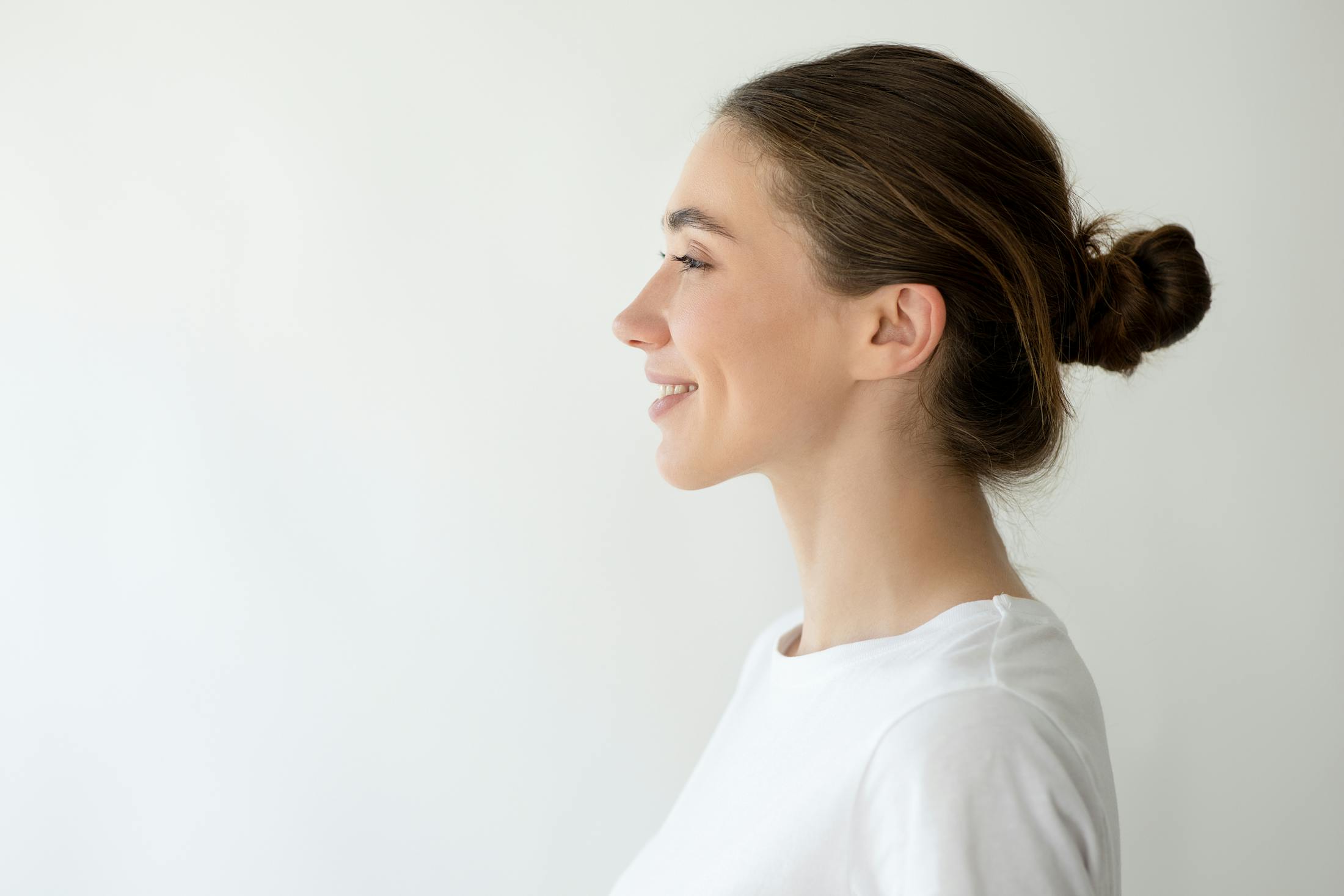woman's side profile in white shirt and bun