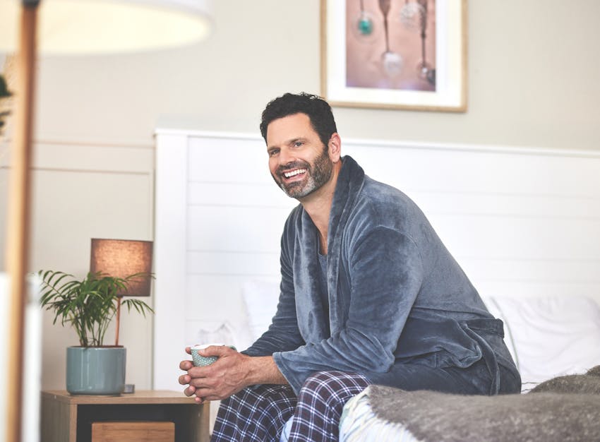 man in blue robe sitting on bed