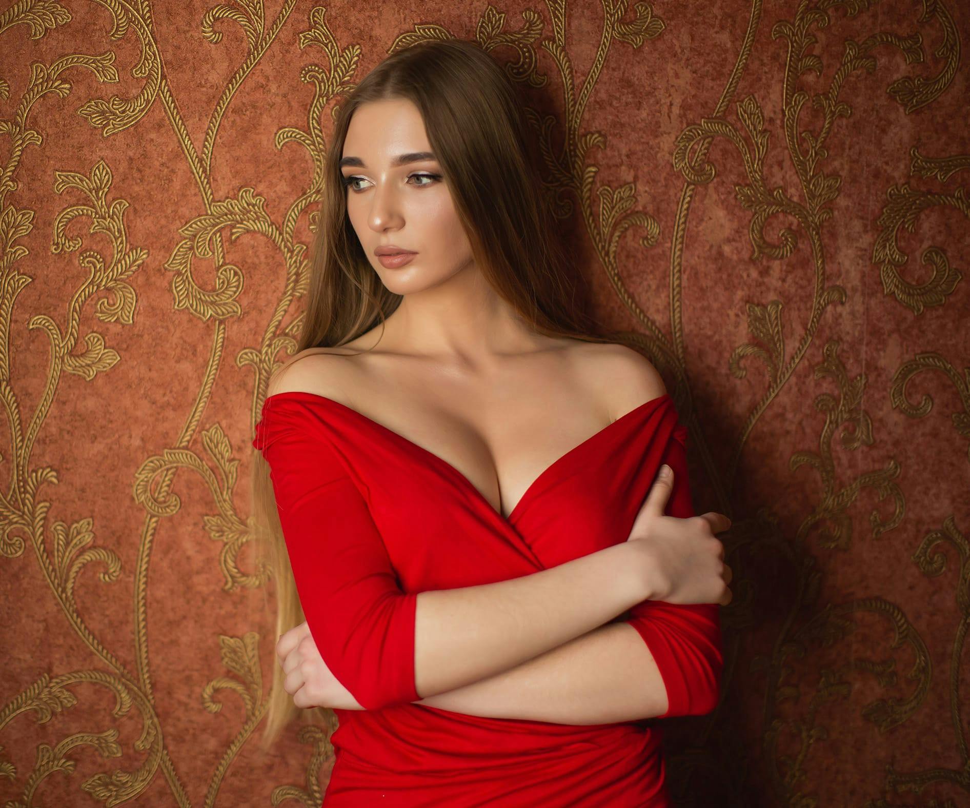 woman wearing a red dress with her arms wrapped around herself