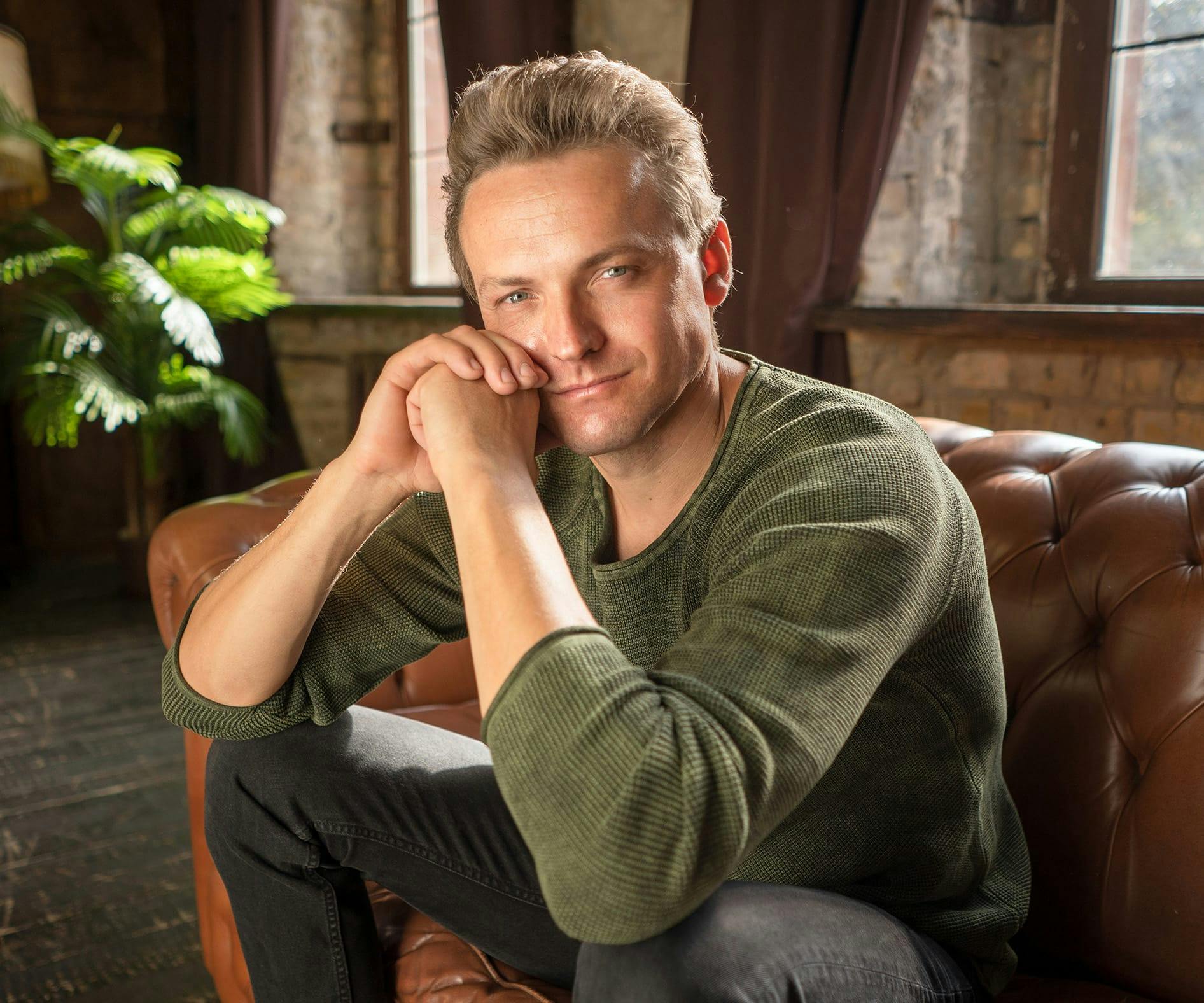 man sitting on leather couch in green sweater