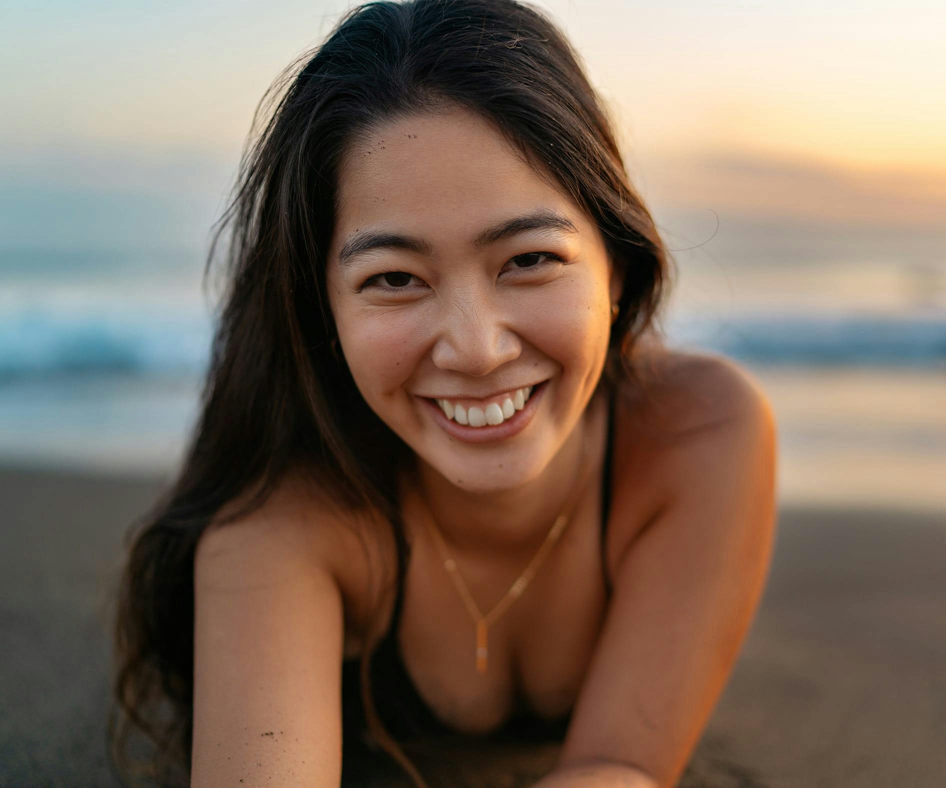asian woman smiling while laying in the sand