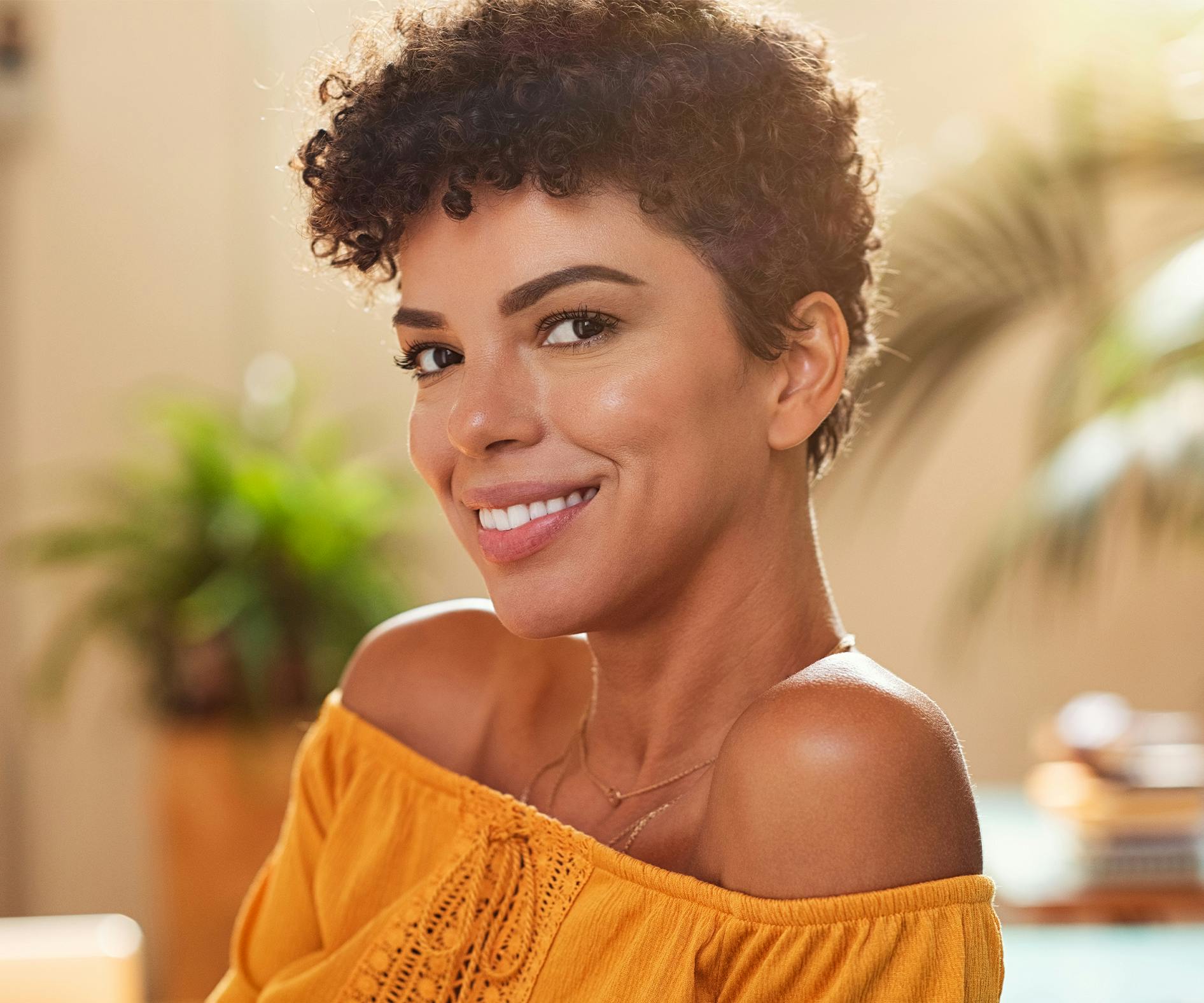 woman with short curly hair in yellow top