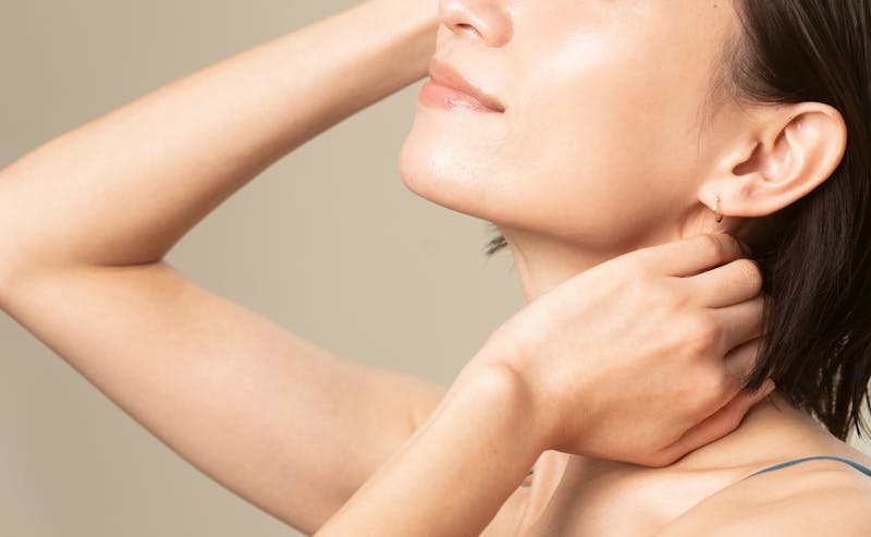 woman touching her head and her neck