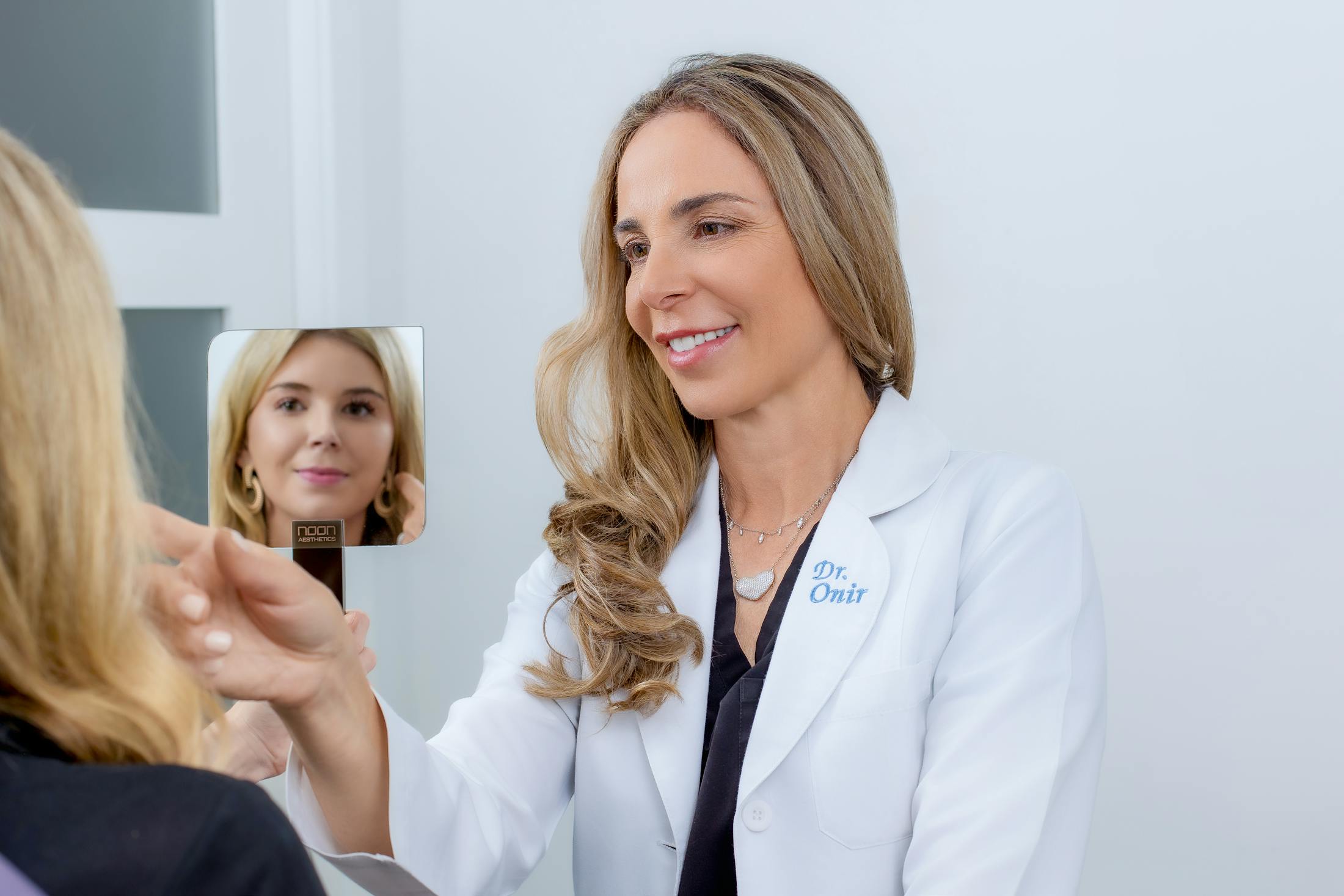 Onir with patient while holding a handheld mirror
