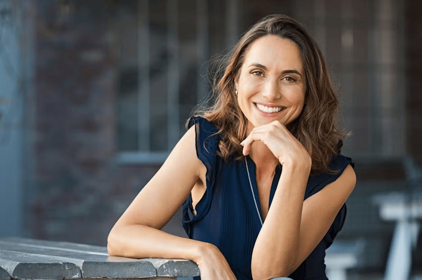 woman smiling with her hand under her chin