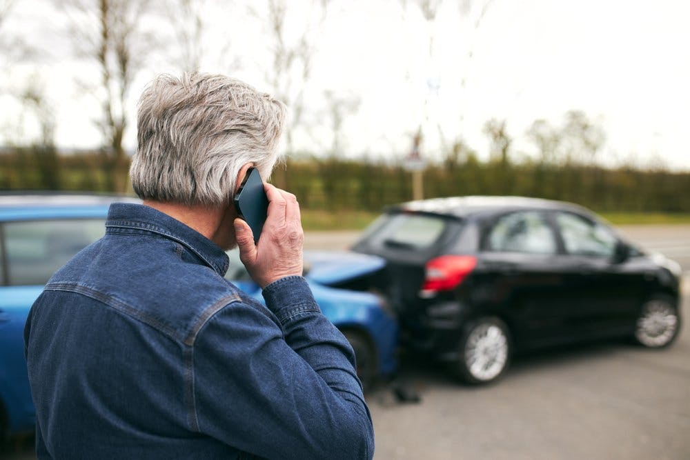 man on the phone looking at car crash