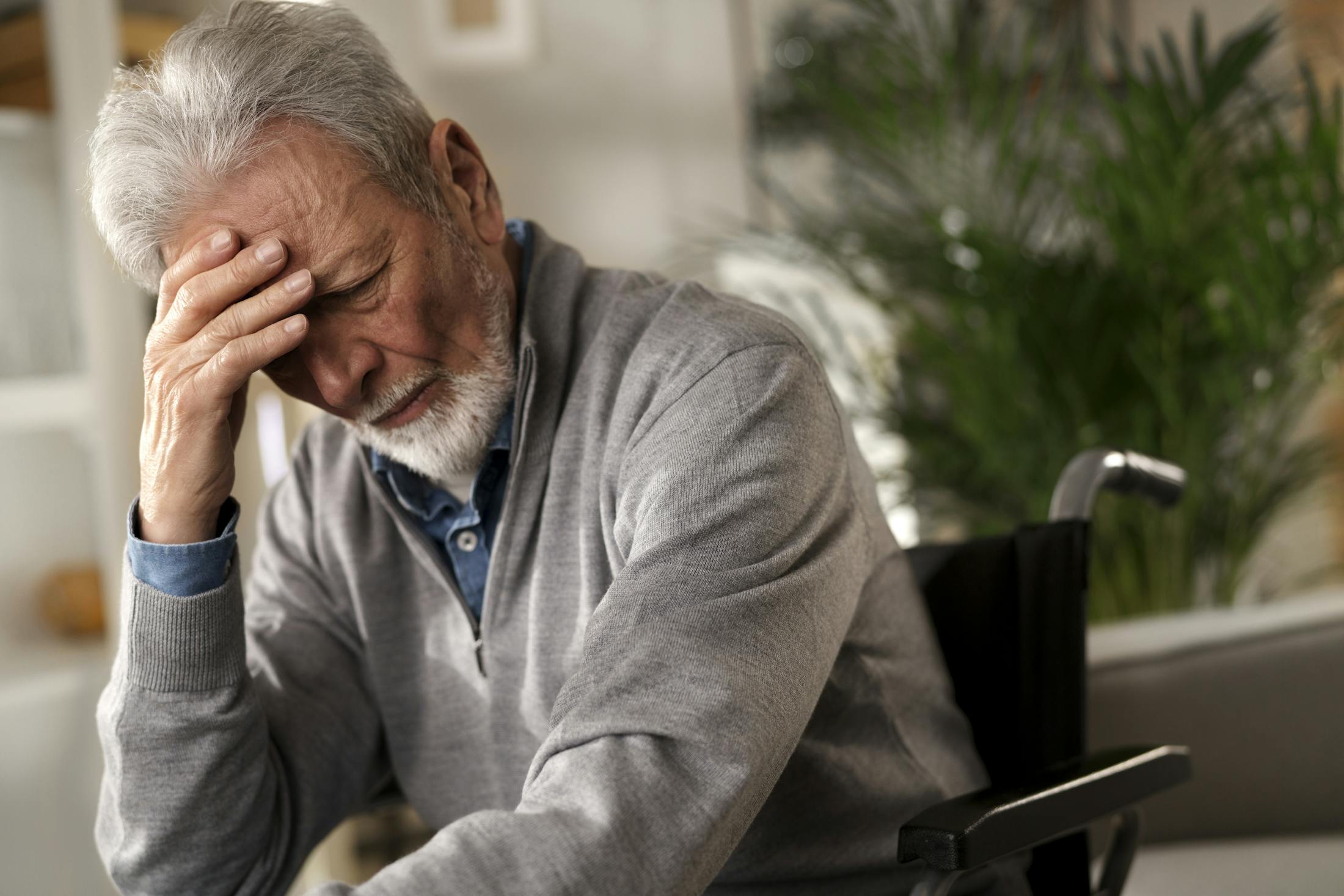 elderly man holding head in hands