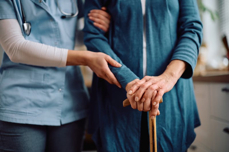 woman with a cane getting assitance to walk