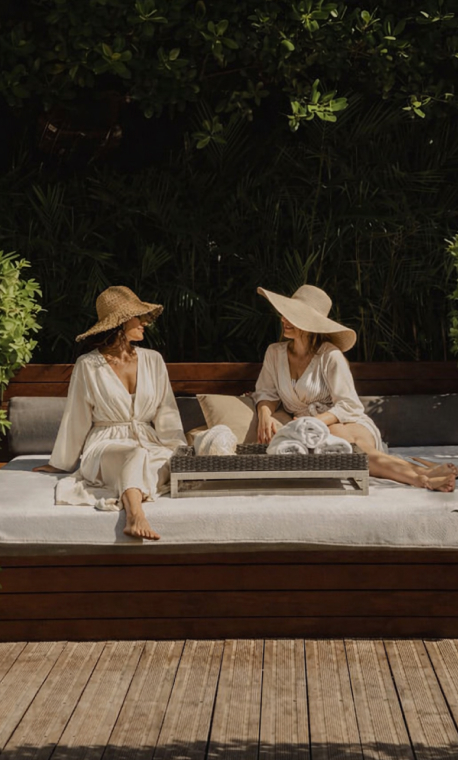 Two women in hats relaxing on a resort sun lounger