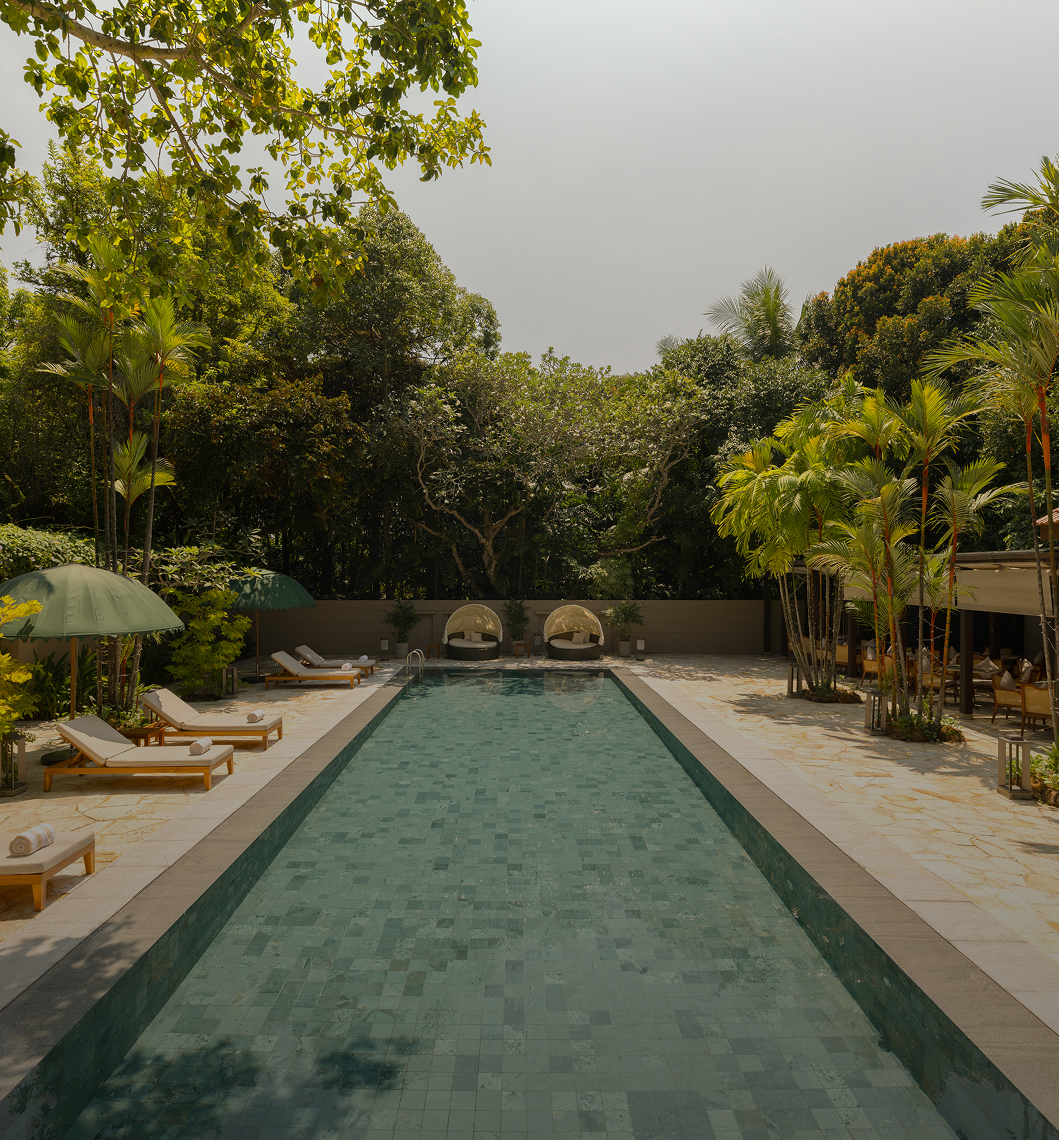 Long thin pool with green tiles set amongst a tropical environment
