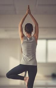 Women balancing on one leg in a yoga studio wearing a grey top