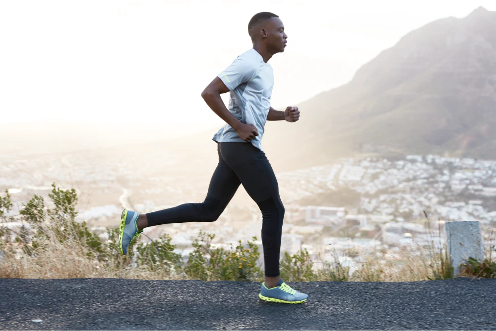 outdoor shot active dark skinned man running morning has regular trainings dressed tracksuit comfortable sneakers concentrated into distance sees finish far away 1