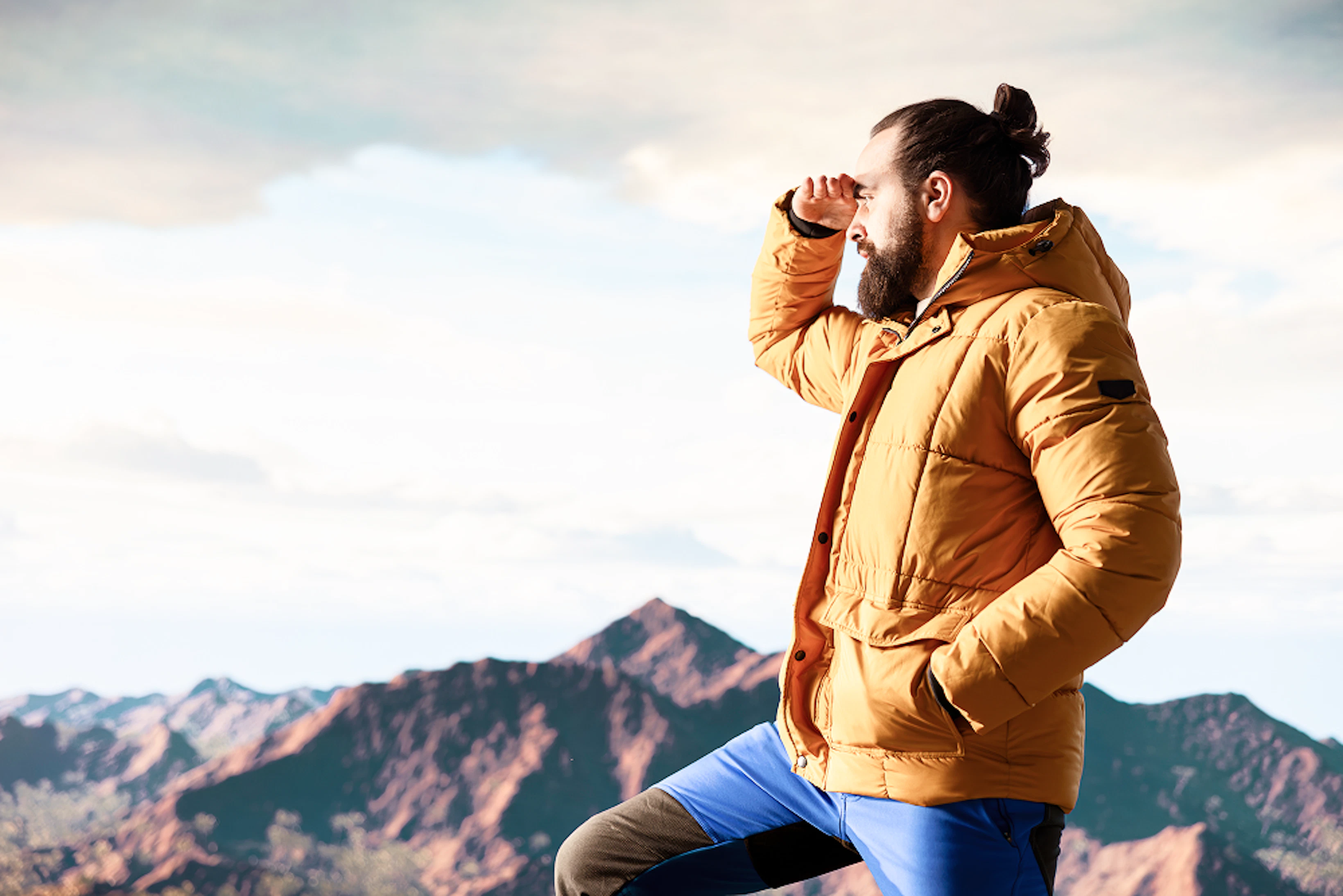 male hiker looks out breathtaking mountain range from hill top 1