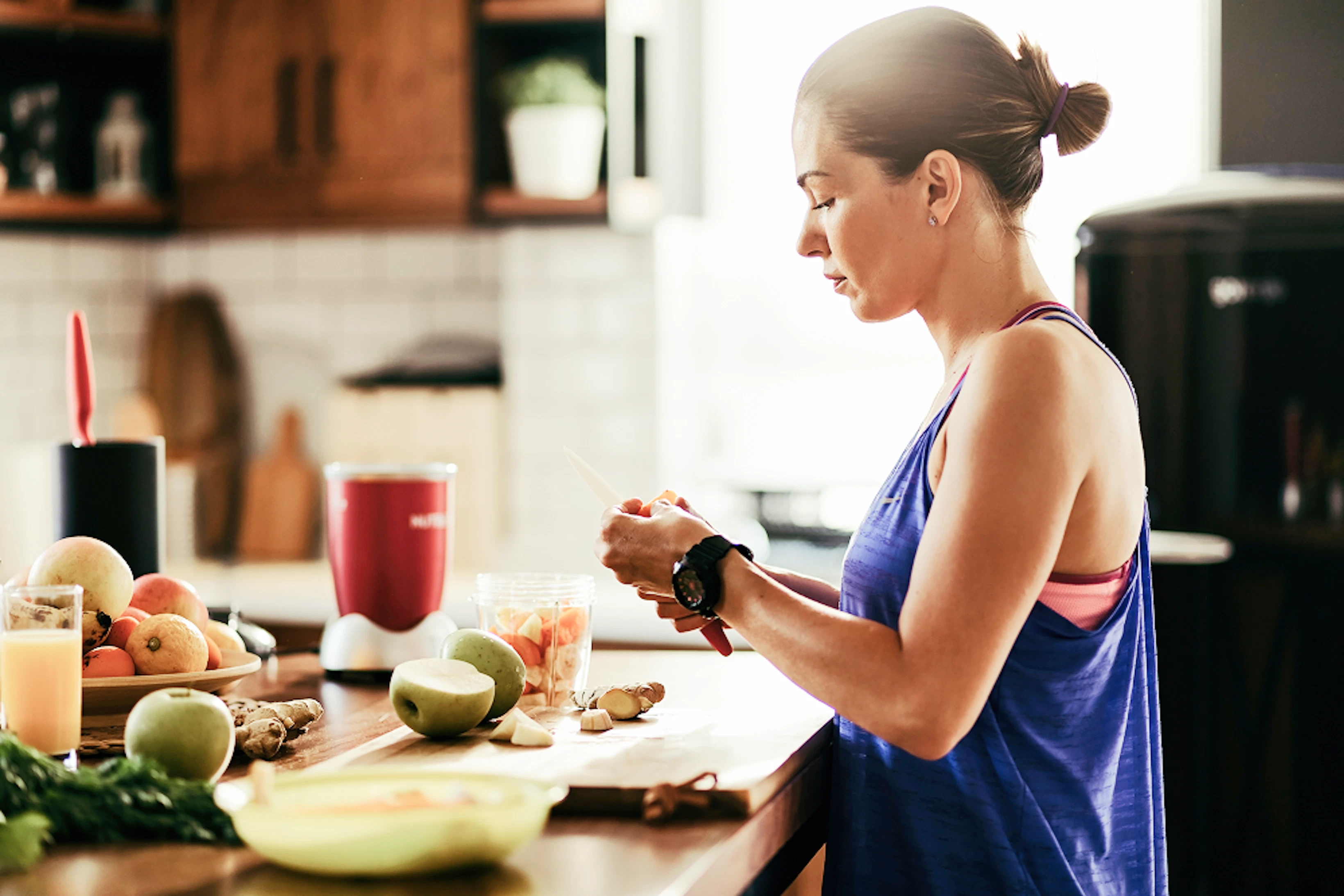 young sportswoman making herself healthy smoothie slicing fresh fruit kitchen 1