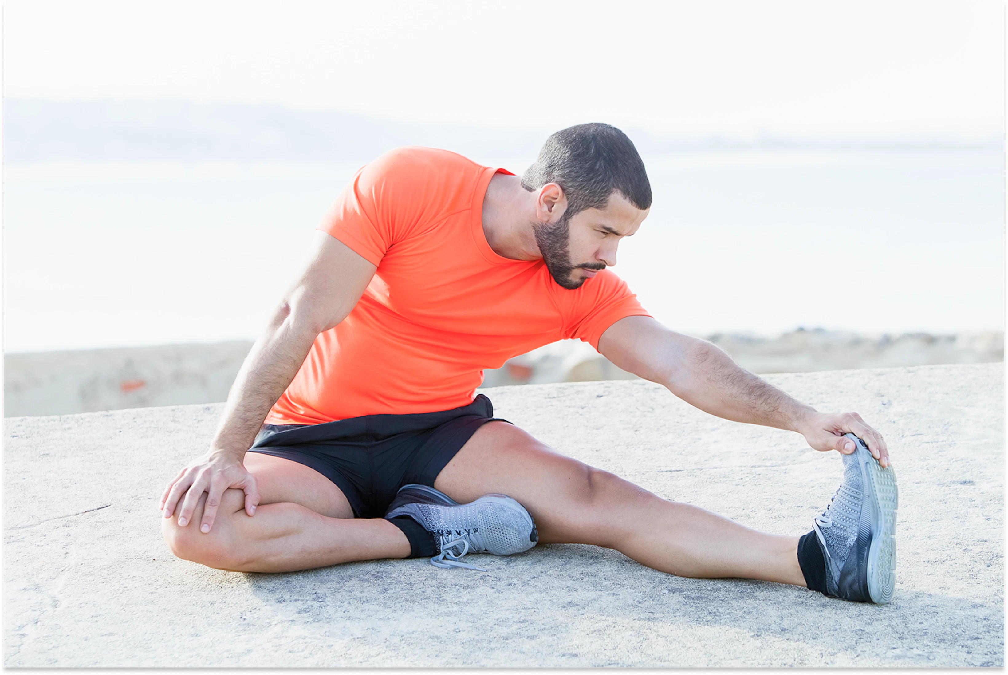 focused strong sporty man stretching legs outdoors 1