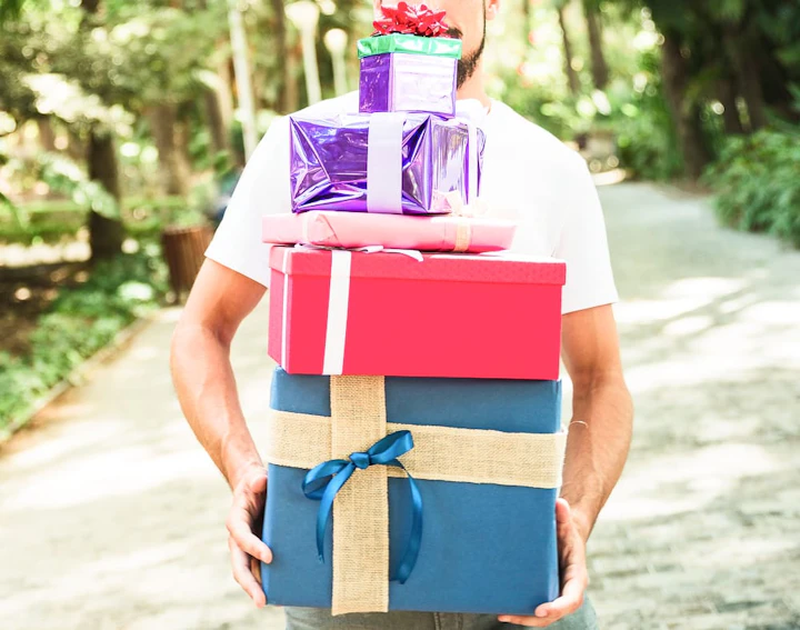 man s hand holding stack multi colored gifts 1