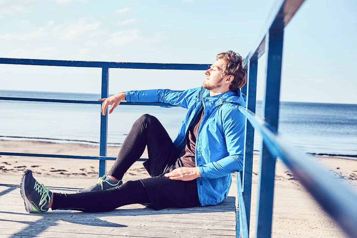sportive young man is chilling near sea while sitting balcony bright sunny day 1